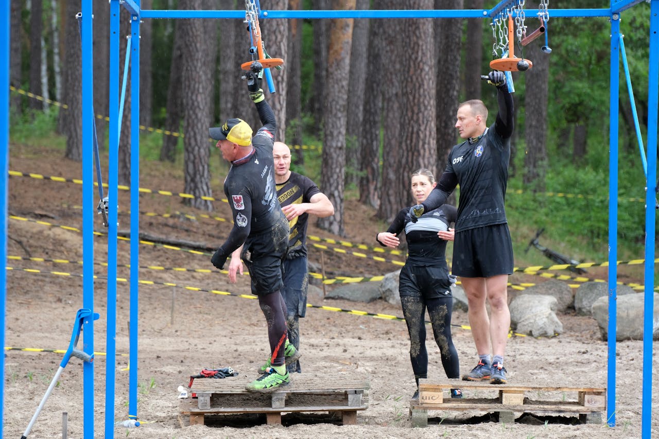 Group of adults navigating an outdoor obstacle course in a forest setting.